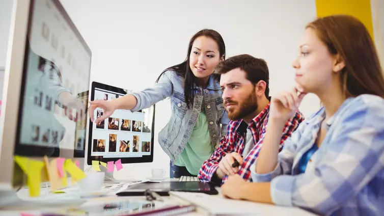 Three people looking at a computer screen.
