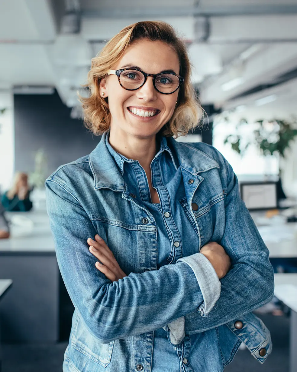 Woman wearing glasses smiling with folded arms.
