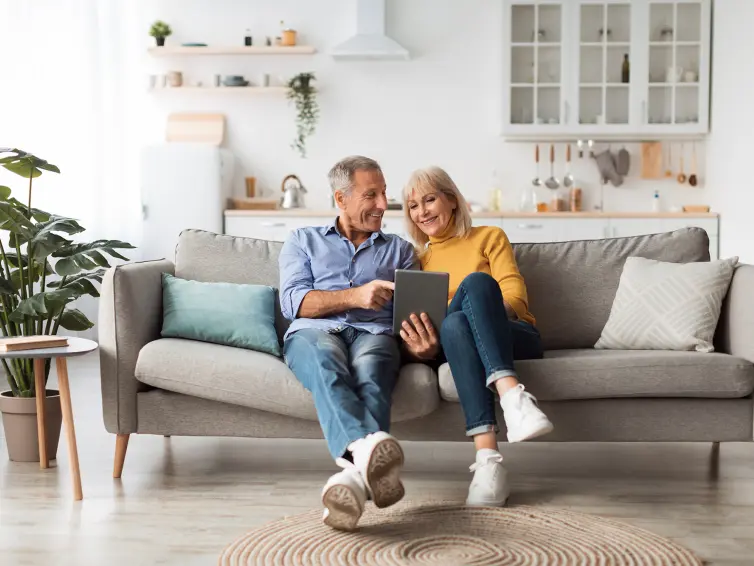 Happy couple sitting on a sofa using a tablet.