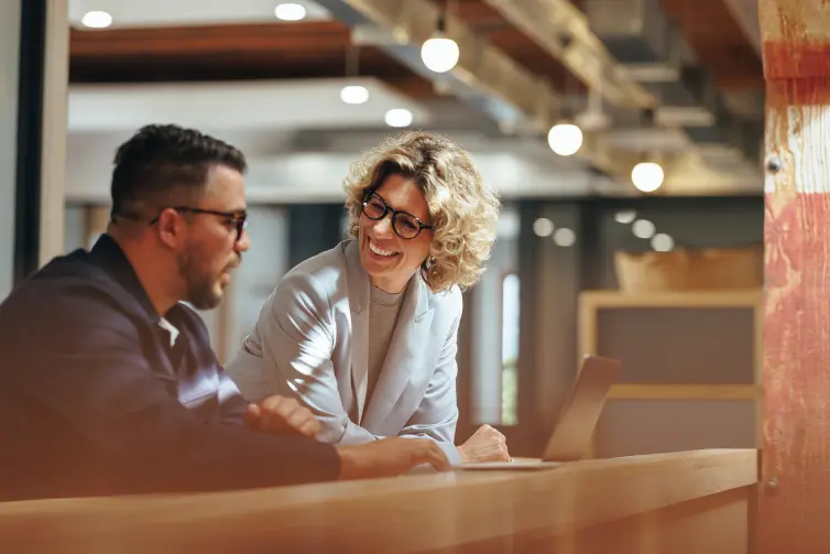 Woman and man at a bar looking at a laptop.