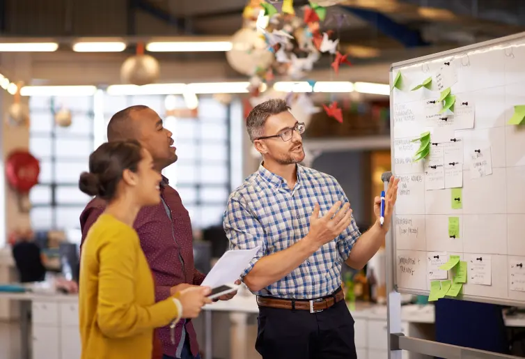 Three people standing in front of a whiteboard.