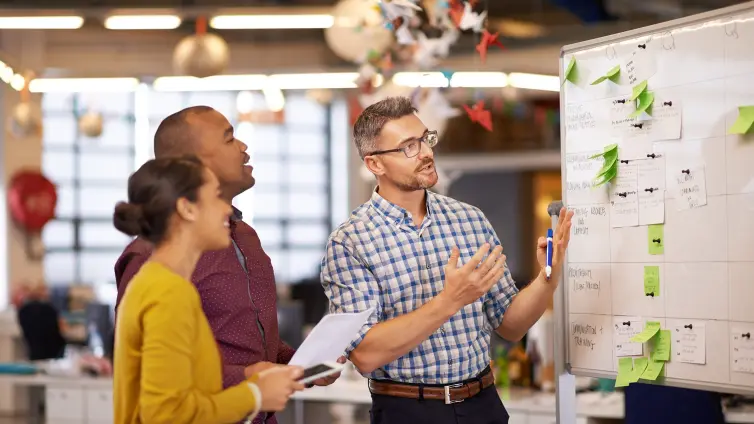 Three people standing in front of a whiteboard.