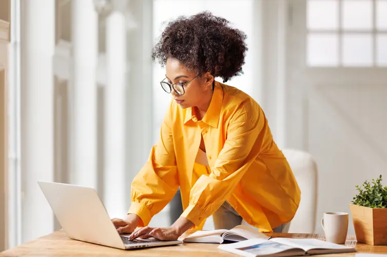 Beautiful smiling ethnic woman works remotely on laptop from home.