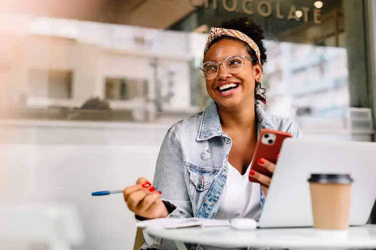 Woman laughing sat in a coffee shop.
